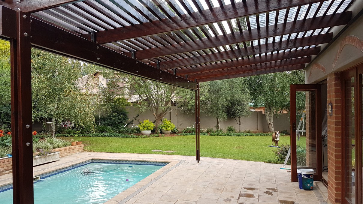 A dog stands outside and looks at the CCA pine pergola and polycarb roofing by Timbermann.